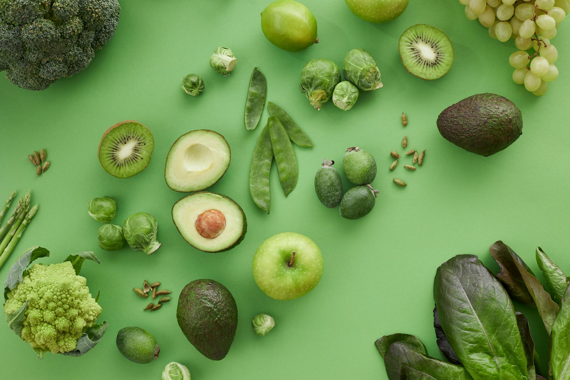close up shot of green fruits and vegetables on a green surface